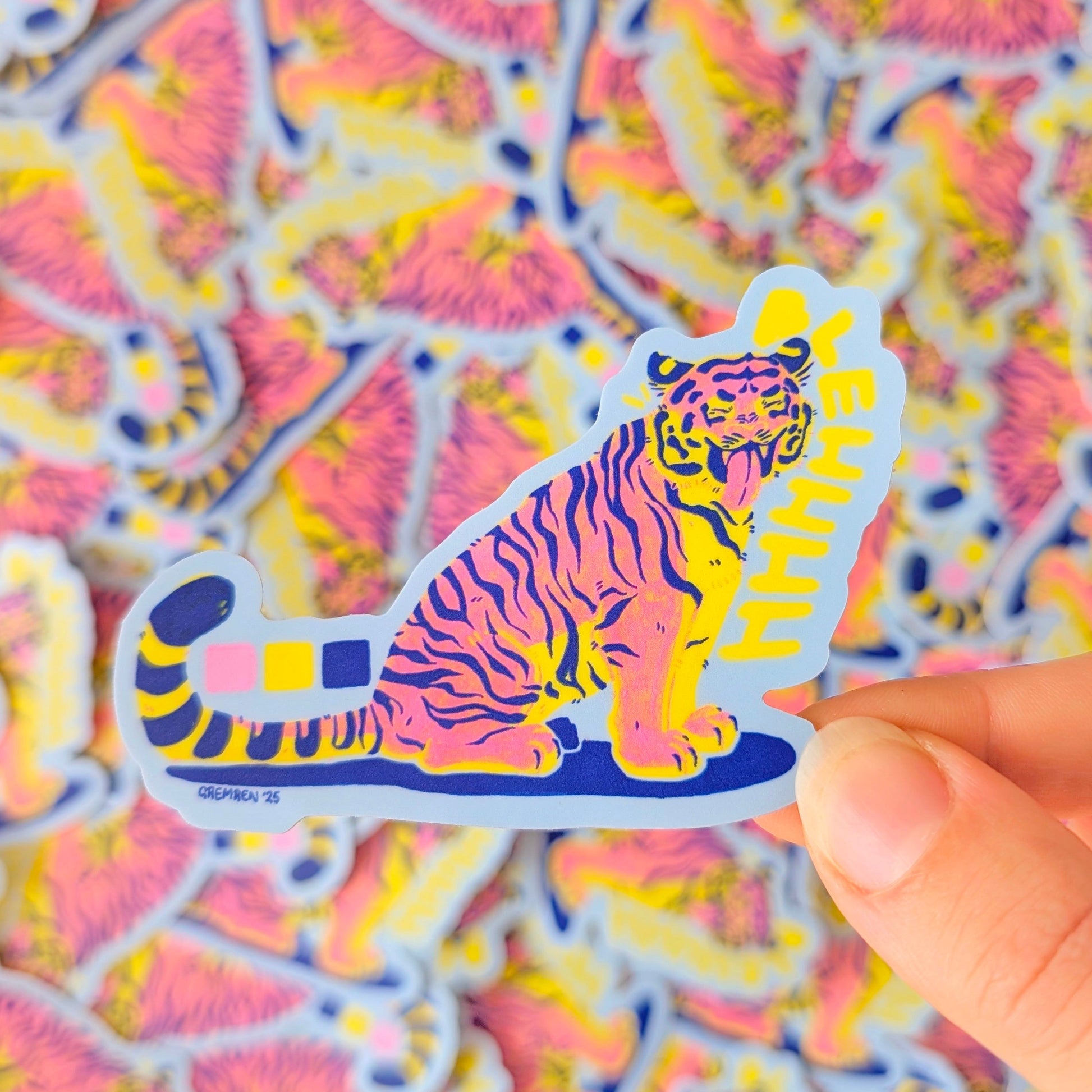 Colorful tiger sticker held over a patterned background